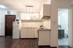 a kitchen with white cabinets and a white refrigerator at Studio Fortuna Park in Sfântu-Gheorghe
