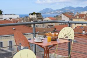 - une table avec un bol de pain et des boissons sur le balcon dans l'établissement L'Esterel, à Cannes