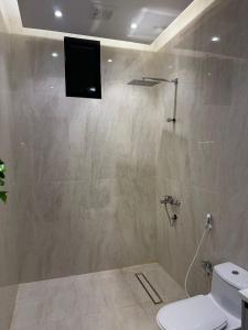 a bathroom with a toilet and a television on the wall at شقق المها وصول ذاتي in Hafr Al Baten
