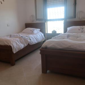 zwei Einzelbetten in einem Zimmer mit Fenster in der Unterkunft סוויטת הנוף בצפת העתיקה in Safed