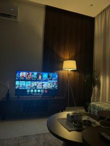 a living room with a large television and a table at شقق المها وصول ذاتي in Hafr Al Baten