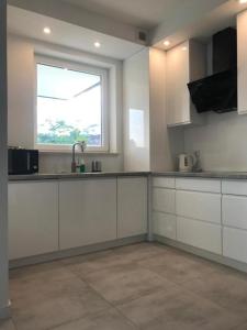 Una cocina con gabinetes blancos y una ventana. en Apartamenty Platinum 3, en Gdansk