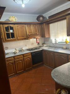 cocina con armarios de madera y lavavajillas negro en Refúgio do Sabor, en Mogadouro 3 fotos más
