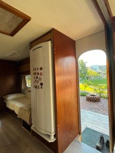 a small room with a refrigerator and a bedroom at Trailer Vintage no Sítio Wanderlust in Rolante