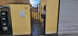 a yellow building with a gate and a metal door at New York Ensuite Double Room in London