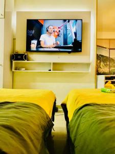 a room with two beds and a tv on a wall at Hotel De Rama Unit 5115 near MOA and NAIA in Manila