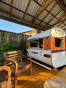 a parked rv parked under a roof with a bench at Trailer Vintage no Sítio Wanderlust in Rolante