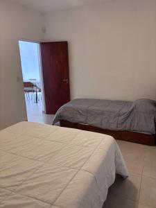 a bedroom with two beds and a door to a balcony at Casa hasta 6 personas in Villa María