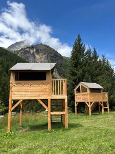two wooden play houses in a field with a mountain at Camping Onlycamp de Tignes in Tignes +19 photos