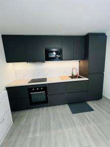 a kitchen with black cabinets and a sink and a microwave at Appartement cosy prêt de Paris Cdg, Astérix , Parc des expositions et Centre de formation CAMAS in Tremblay-En-France