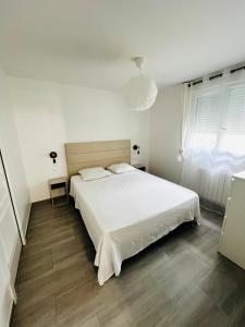 a white bedroom with a white bed and a window at Appartement cosy prêt de Paris Cdg, Astérix , Parc des expositions et Centre de formation CAMAS in Tremblay-En-France