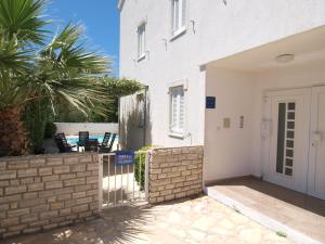 a white house with a gate and a palm tree at Olea Apartments in Srima