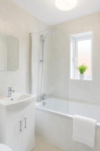 Un baño blanco con bañera y lavabo. en Spacious Home in Washington, en Washington