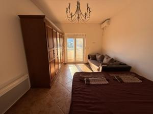 a bedroom with a bed and a couch and a chandelier at Simple Stay in Buljarica