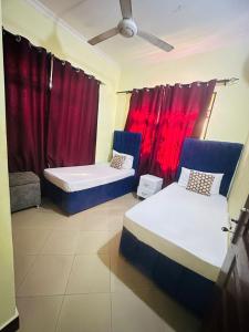 2 letti in una camera con tende rosse di Pearl Lulu -3 Bedroom Apartments near Zanzibar Ferry and DownTown a Dar es Salaam Altre 48 foto