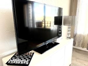 ein großer Flachbildfernseher auf einer Kommode in der Unterkunft White dream in Gréolières les Neiges