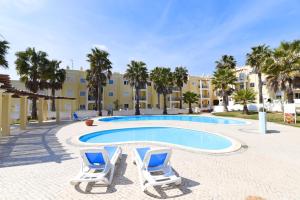 a swimming pool with two lounge chairs and a building at Praia da Lota Beachfront Resort - Hotel & Apartments in Manta Rota