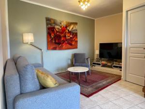 a living room with a blue couch and a tv at Domaine du Petit Tournebelle in Gruissan