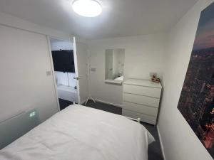 a small white bedroom with a bed and a window at Peaceful Garden Cabin Stay in the Yorkshire Wolds in Cranswick
