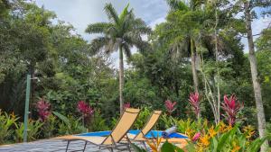 two chairs and a table and some palm trees at Villas Pura Vida - Guapinol in Río Negro