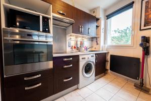 a kitchen with a washing machine and a microwave at World of Disneyland, 4 personnes, Wifi in Chanteloup-en-Brie