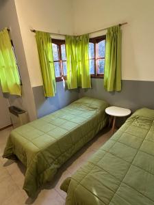 2 Betten in einem Zimmer mit grüner Bettwäsche und Fenstern in der Unterkunft Casa Villa Elisa Rio Tercero in Río Tercero