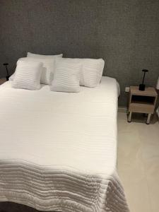 a large bed with white sheets and pillows at Manglar - Ciudad Mallorquin in Puerto Colombia