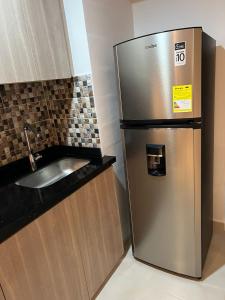 a kitchen with a stainless steel refrigerator next to a sink at Manglar - Ciudad Mallorquin in Puerto Colombia