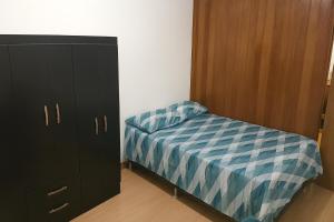 a small bedroom with a bed and a cabinet at Estúdio bem localizado e completo em Teresópolis in Teresópolis +3 photos