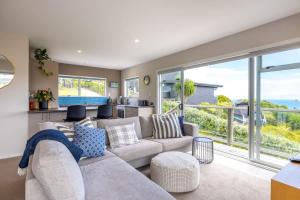 a living room with a couch and a large window at Sea View Serenity in Waiheke Island