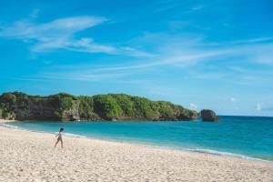 a person walking on a beach near the ocean at Minatogawa Stay OKINAWA in Yaese