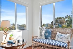 a wicker bench in a room with windows at Cooee Bay Beach House in Yeppoon