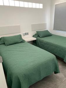 two beds in a room with green sheets at Casa GALLARDO in Manzanillo