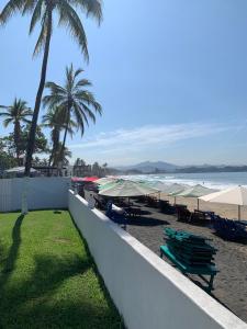 a beach with chairs and umbrellas and the ocean at Casa GALLARDO in Manzanillo