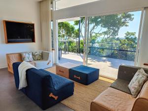 a living room with a blue couch and a large window at The Pool House in Lennox Head