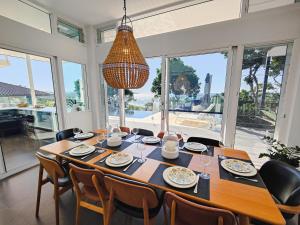 a dining room with a table and chairs and a chandelier at The Pool House in Lennox Head