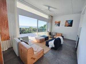 a living room with a couch and a large window at The Pool House in Lennox Head +21 photos