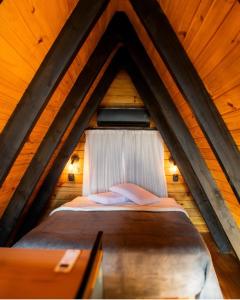 a bed in a wooden attic with a window at Cipó Chalés in Jaboticatubas