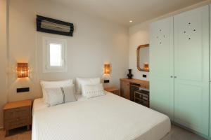 a bedroom with a white bed and a mirror at Phoenicia Nature Naxos in Kastraki
