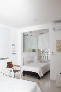 ein weißes Schlafzimmer mit einem Bett und einem Stuhl in der Unterkunft Encantador Apartamento El Laguito Bocagrande in Cartagena de Indias