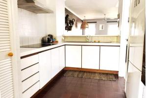 Una cocina con gabinetes blancos y piso de baldosas. en Sea Breeze Villawalk Everywheresunsets, en Fremantle
