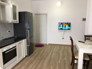 a kitchen with a table and a tv on the wall at Ornela Apartments in Durrës