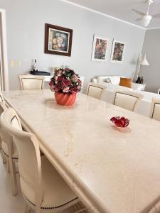 a dining room table with a vase of flowers on it at Riviera de São Lourenço, pé na grama in Bertioga +54 photos