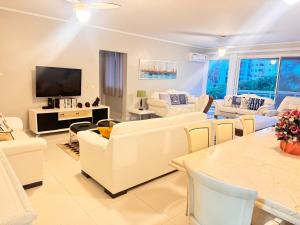 a living room with white furniture and a flat screen tv at Riviera de São Lourenço, pé na grama in Bertioga