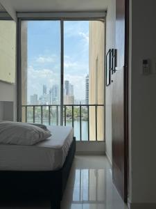 ein Schlafzimmer mit einem Bett und einem großen Fenster in der Unterkunft Encantador Apartamento El Laguito Bocagrande in Cartagena de Indias