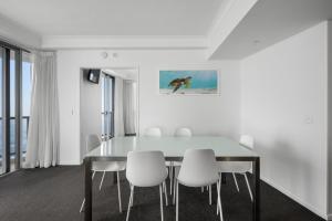 une salle à manger avec une table en verre et des chaises blanches dans l'établissement Towers of Chevron - Private Apartments - Hosted by Coastal Letting Co., à Gold Coast