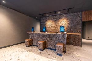 a bar with stools in a room with a brick wall at HOTEL R9 Premium Kawamataekimae in Ōra