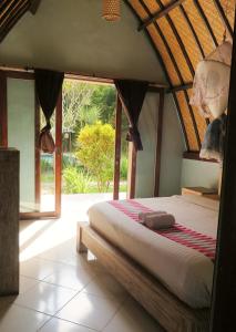 a bed in a room with a large window at Apit Lawang Villas in Nusa Penida