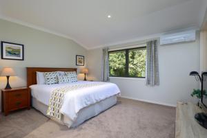 a white bedroom with a bed and a window at Hazelwood Mapua in Mapua