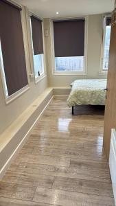 a bedroom with a bed and two windows at City Views Top Floor - Bradford City Center in Bradford